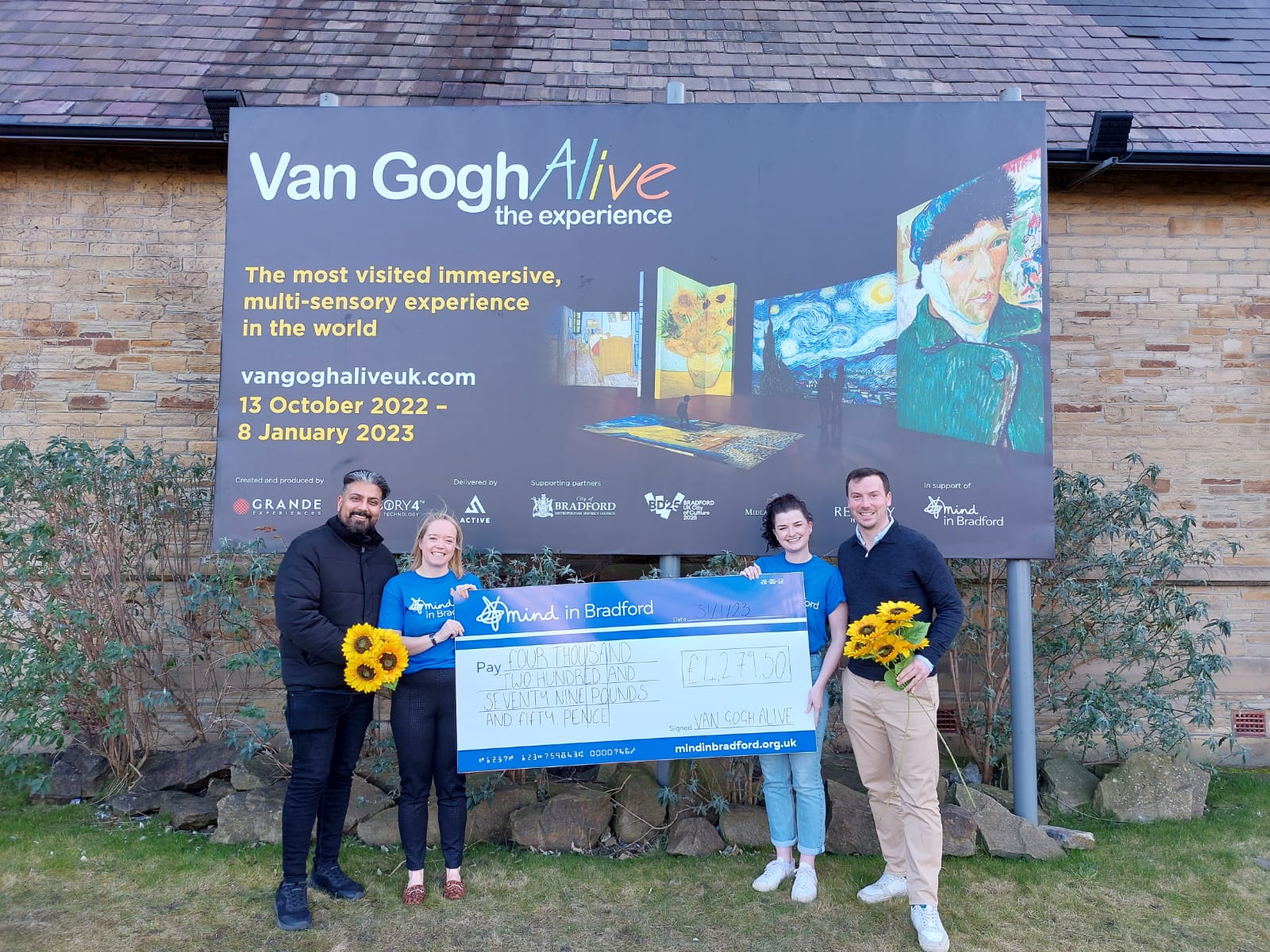 Two men and woman with giant cheque outside Van Gogh Alive