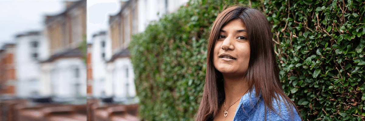 Woman standing beside a residential street smiling into the camera