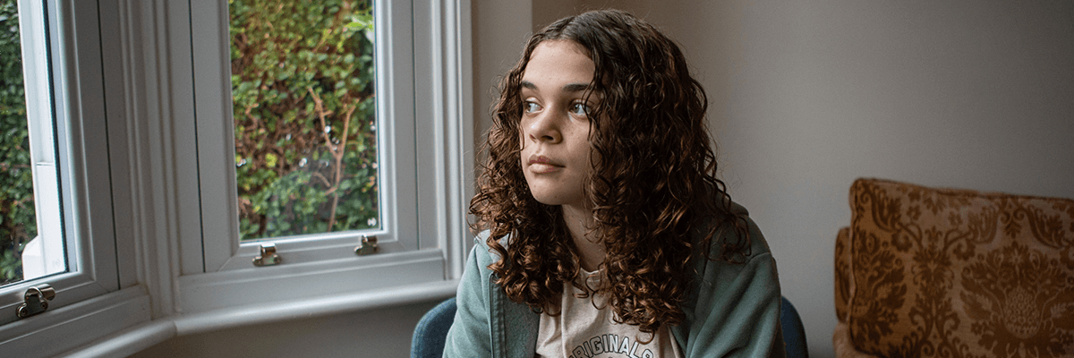 Young girl looking out of the window at home