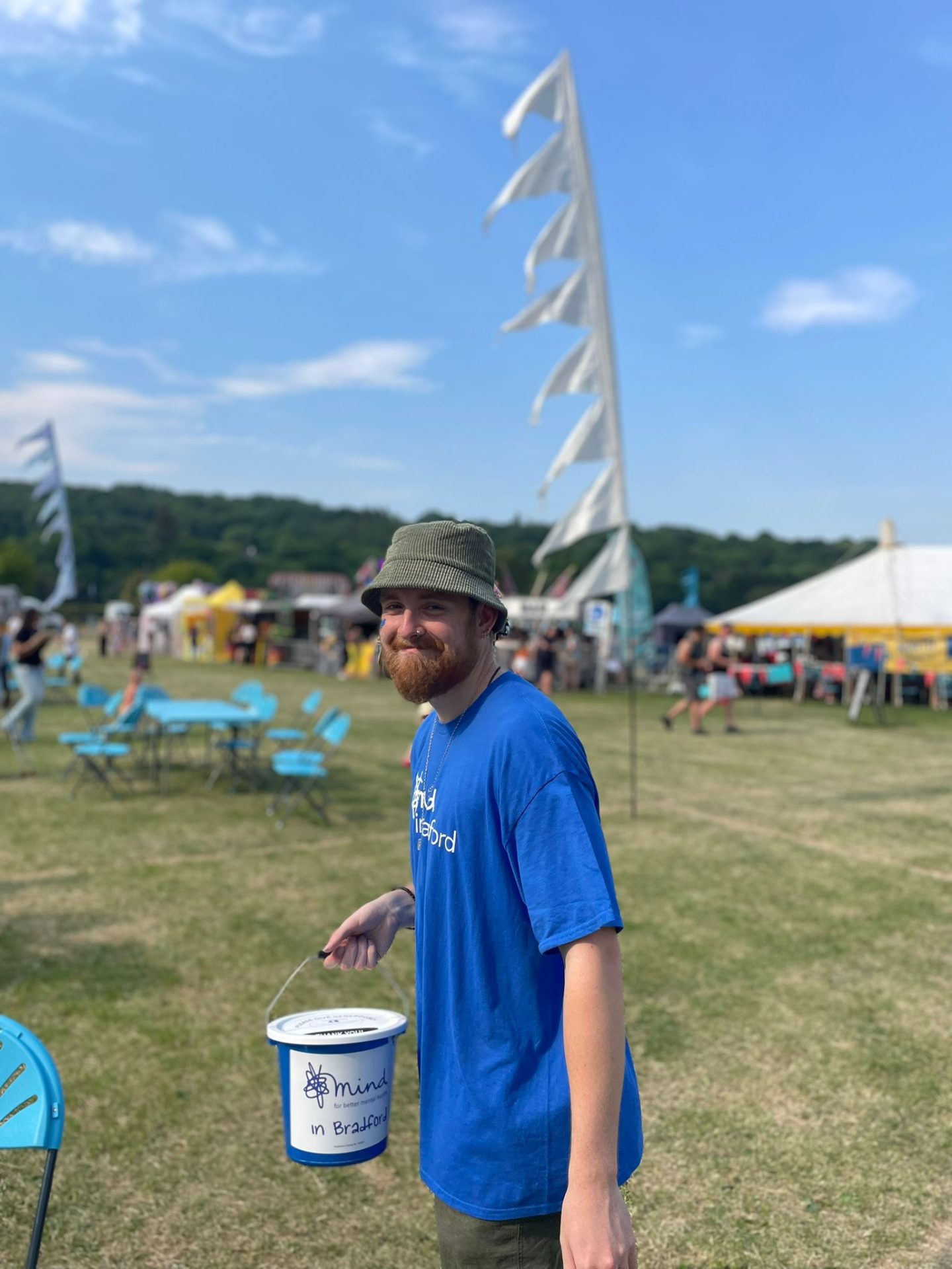 Smiling man in blue top holding a fundraising bucket